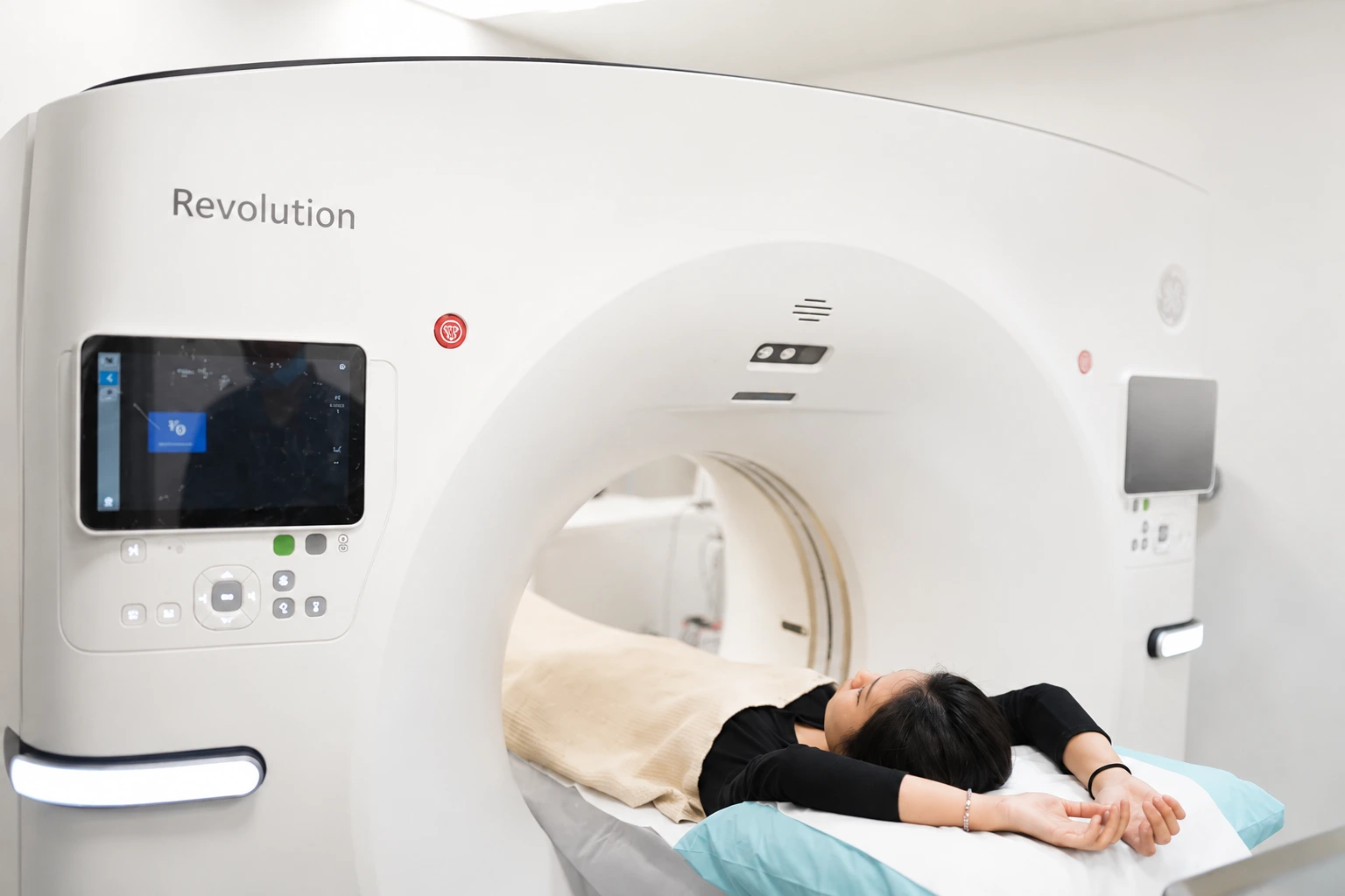 A patient lying on the bed of a CT scanner about to enter the gantry for a CT coronary angiogram at a Singapore clinic